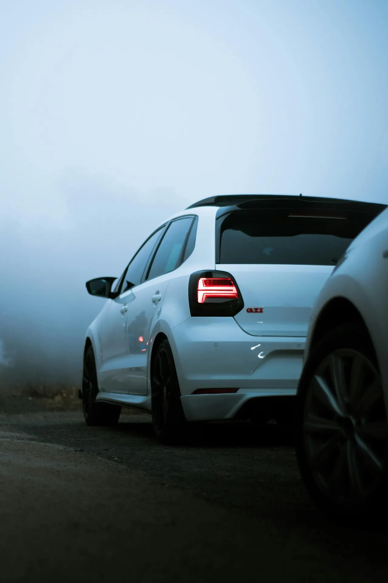 Volkswagen Polo GTI bianca, una compatta del gruppo Volkswagen, parcheggiata su una strada avvolta dalla nebbia